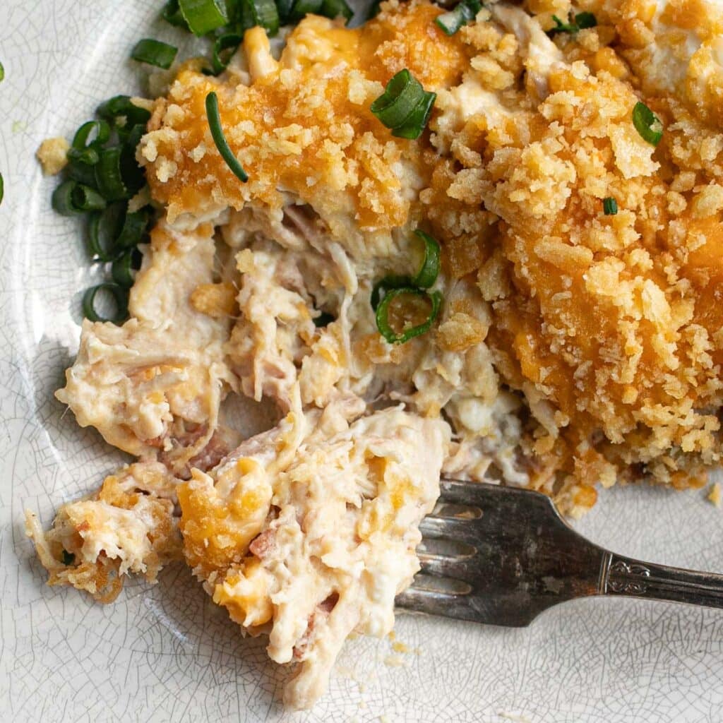 a serving of million dollar chicken casserole on a white plate with a fork