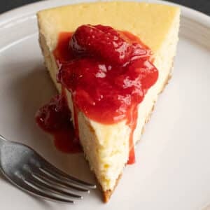 a slice of New York Cheesecake topped with strawberry sauce
