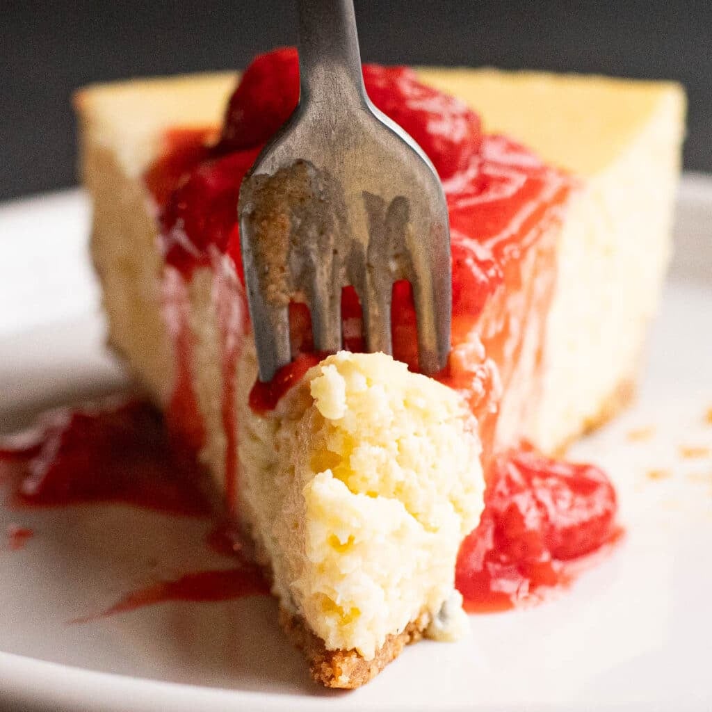 a fork slicing into a piece of New York Cheesecake