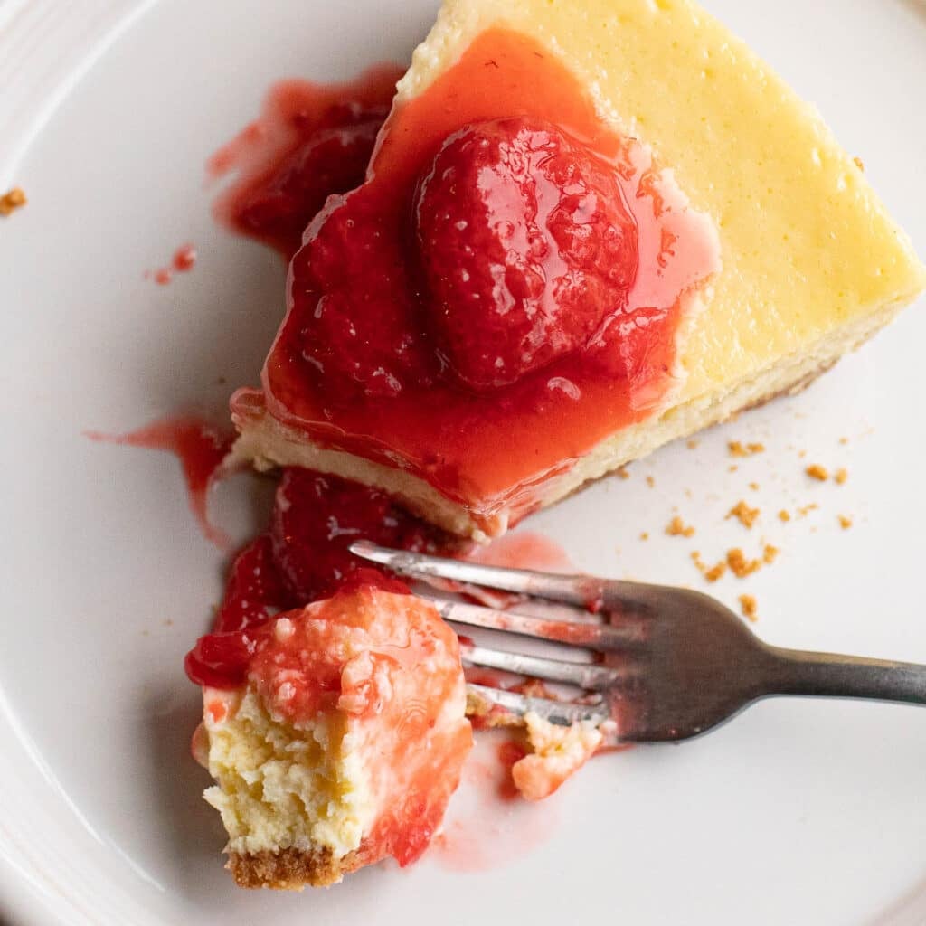 overhead view of a slice of New York Cheesecake topped with strawberry compote