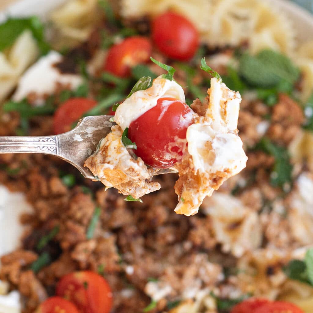 a fork holding a cherry tomato and yogurt sauce