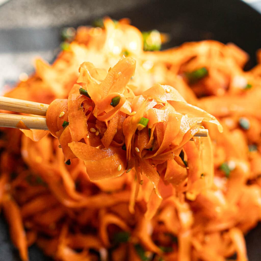 chopsticks holding carrot ribbon salad