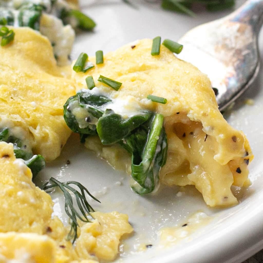 a fork holding a bite of a cottage cheese omelet 