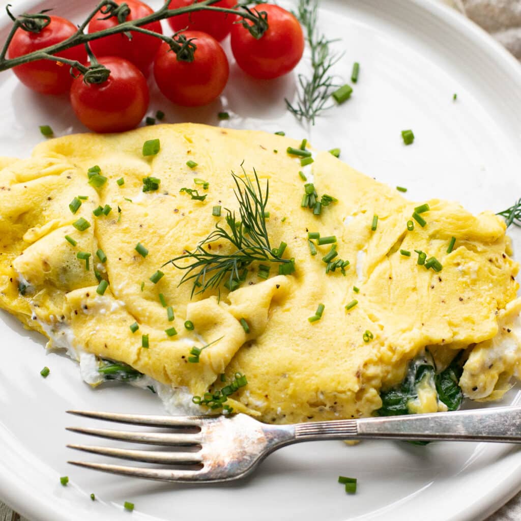 cottage cheese omelet  topped with chopped chives and fresh dill on a white plate