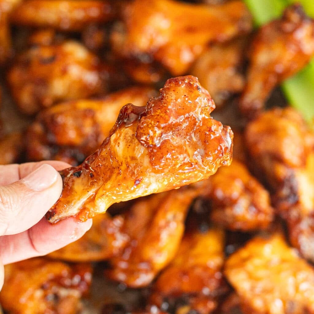a hand holding one hot honey chicken wing