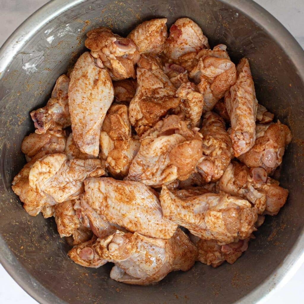 seasoned uncooked chicken wings in a mixing bowl