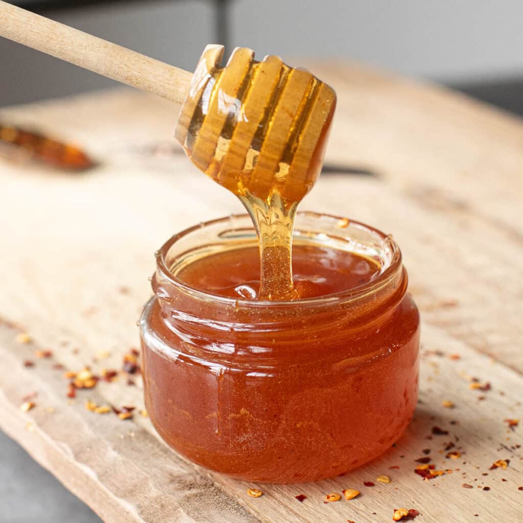 a honey wand dipping into a jar of hot honey