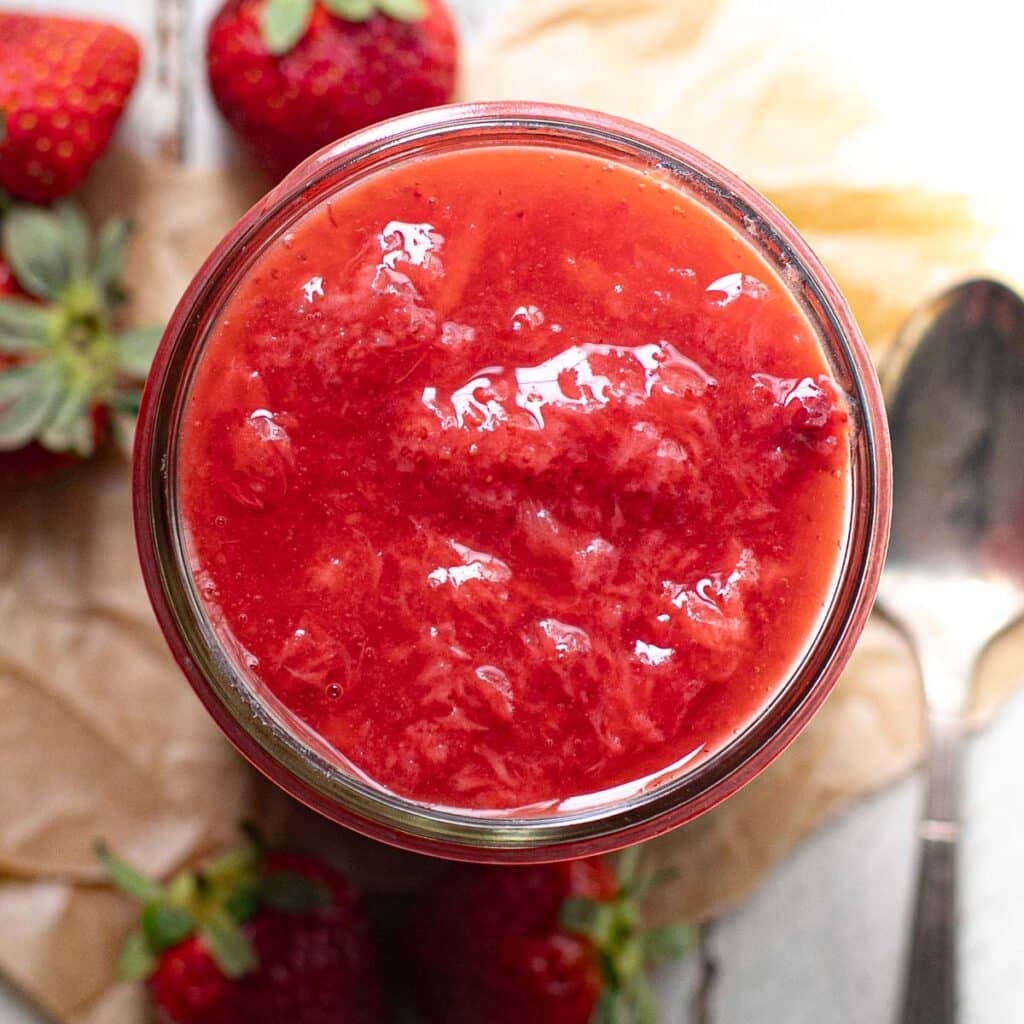 overhead view of strawberry sauce in a glass jar