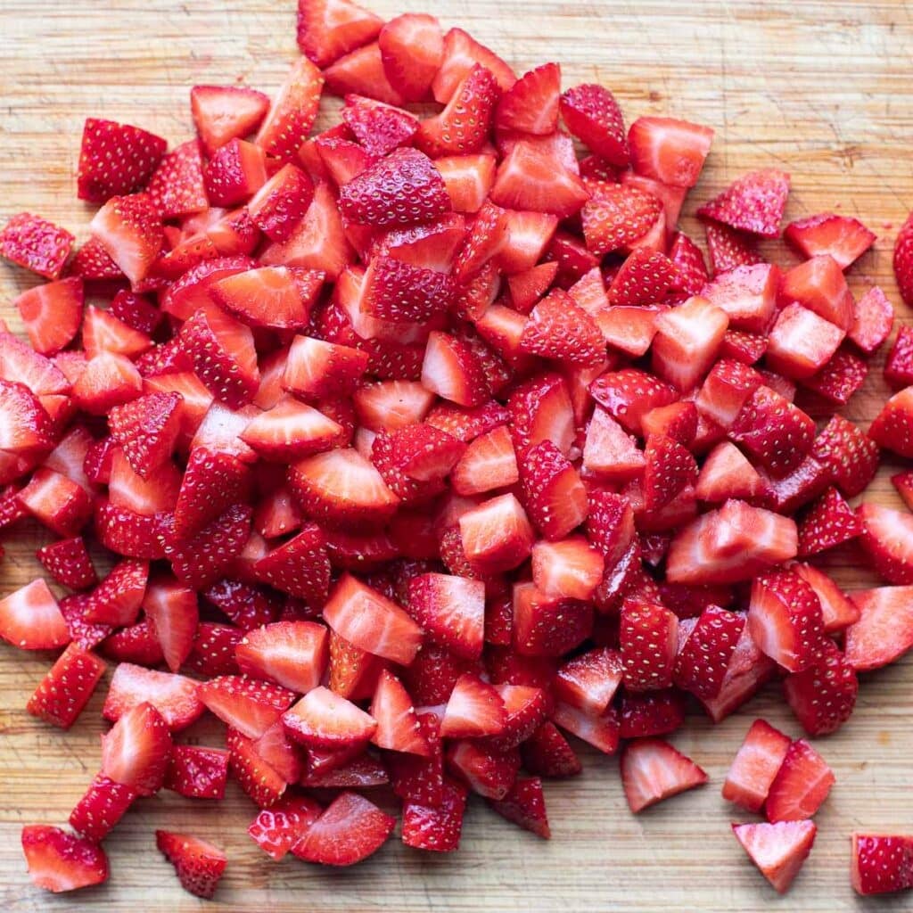 chopped strawberries on a wooden cutting board