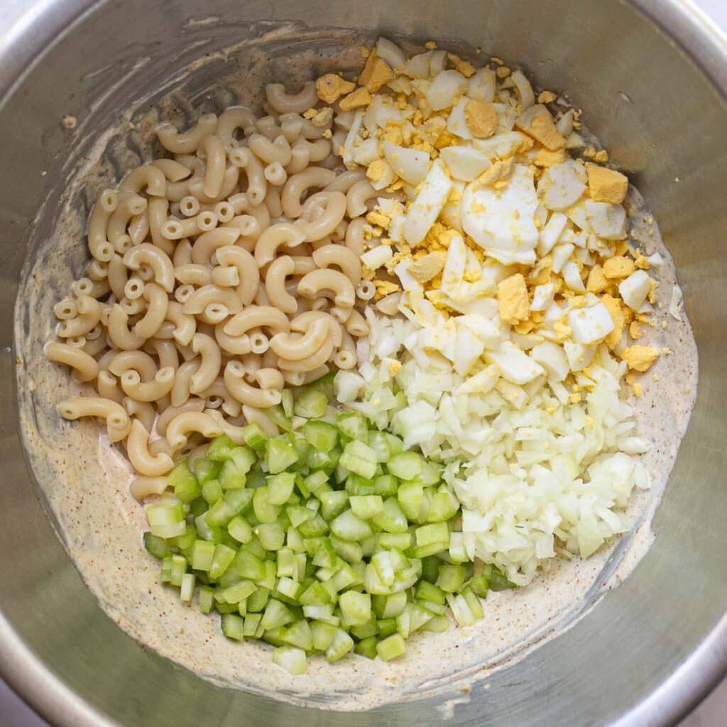 elbow macaroni, chopped celery, chopped eggs and onions in a mixing bowl