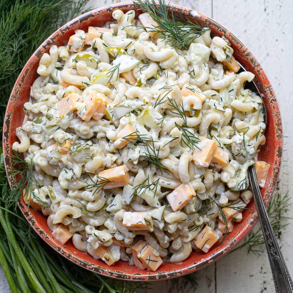 dill pickle macaroni salad in an orange serving bowl