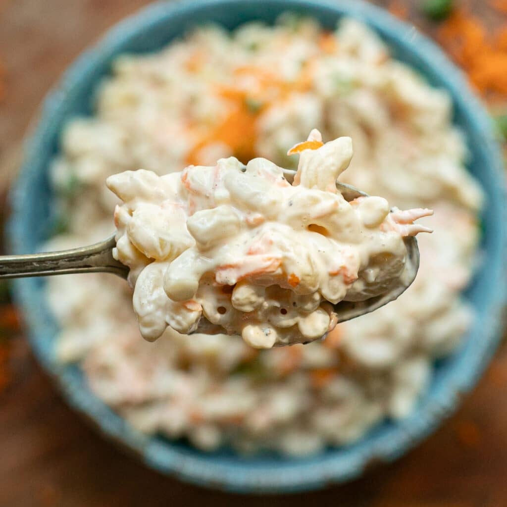 a large serving spoon holding Hawaiian macaroni salad