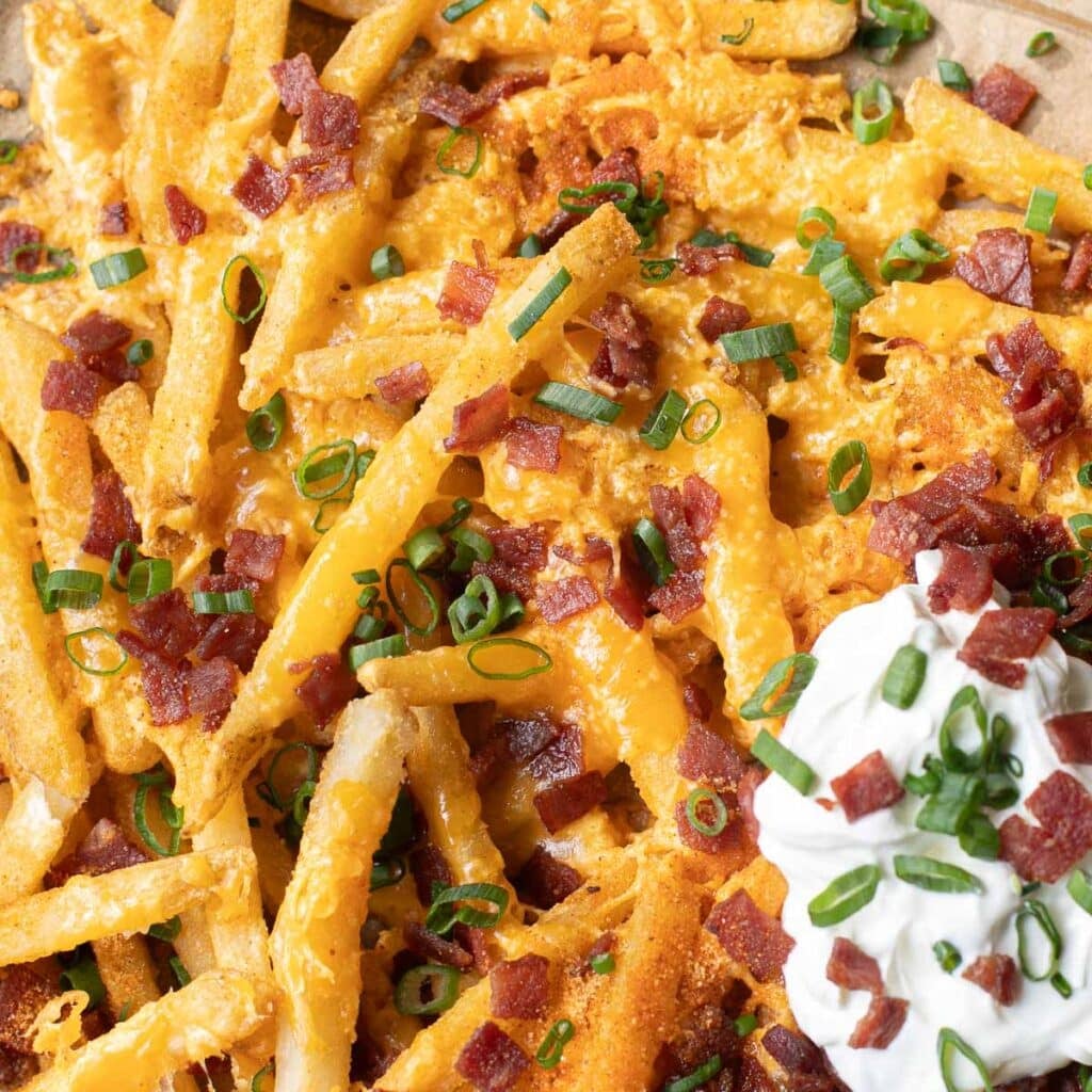 close up view of loaded fries topped with bacon and chopped scallions