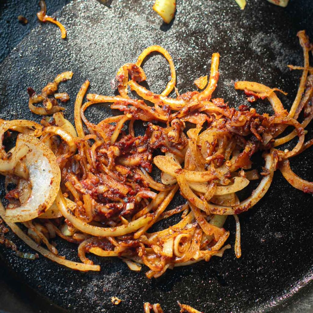sauteed onions and tomato in a cast iron pan