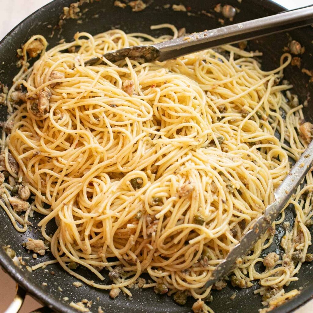 pasta being tossed with sauce in a pan