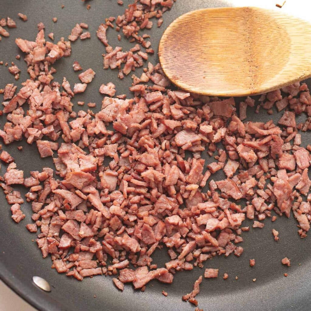 cooked diced bacon in a frying pan