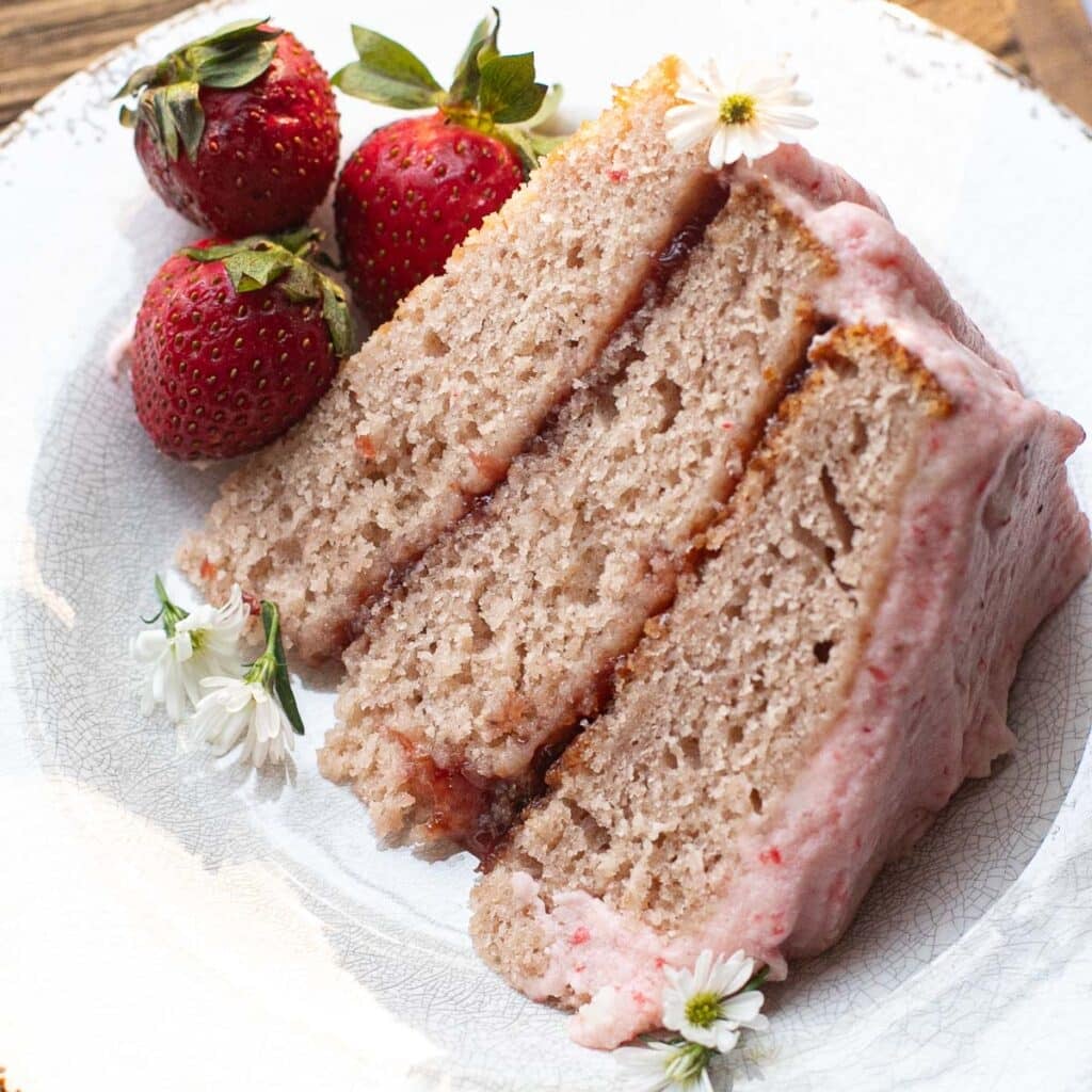 a slice of strawberry cake with strawberry filling on a white plate
