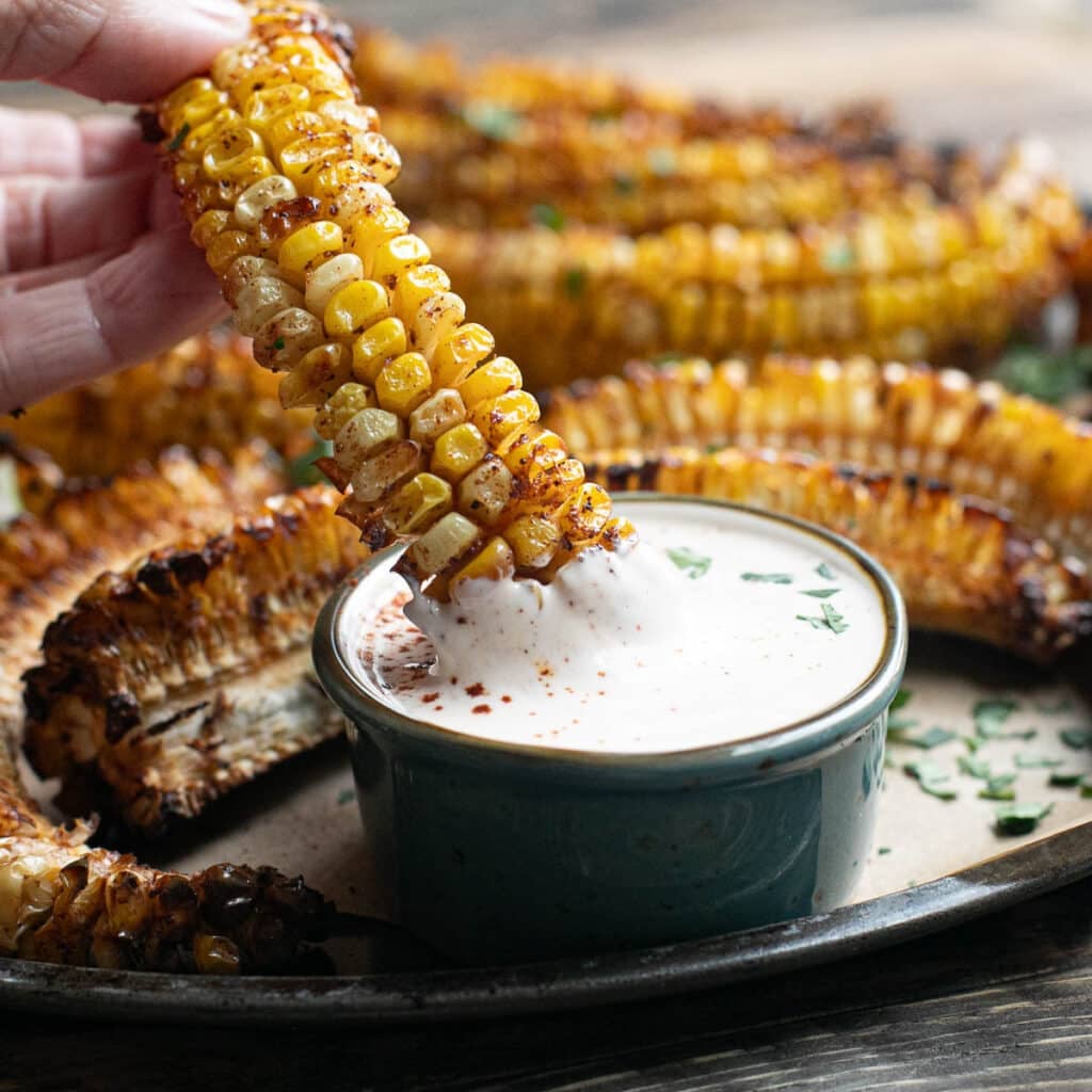 a corn rib being dipped in a creamy sauce