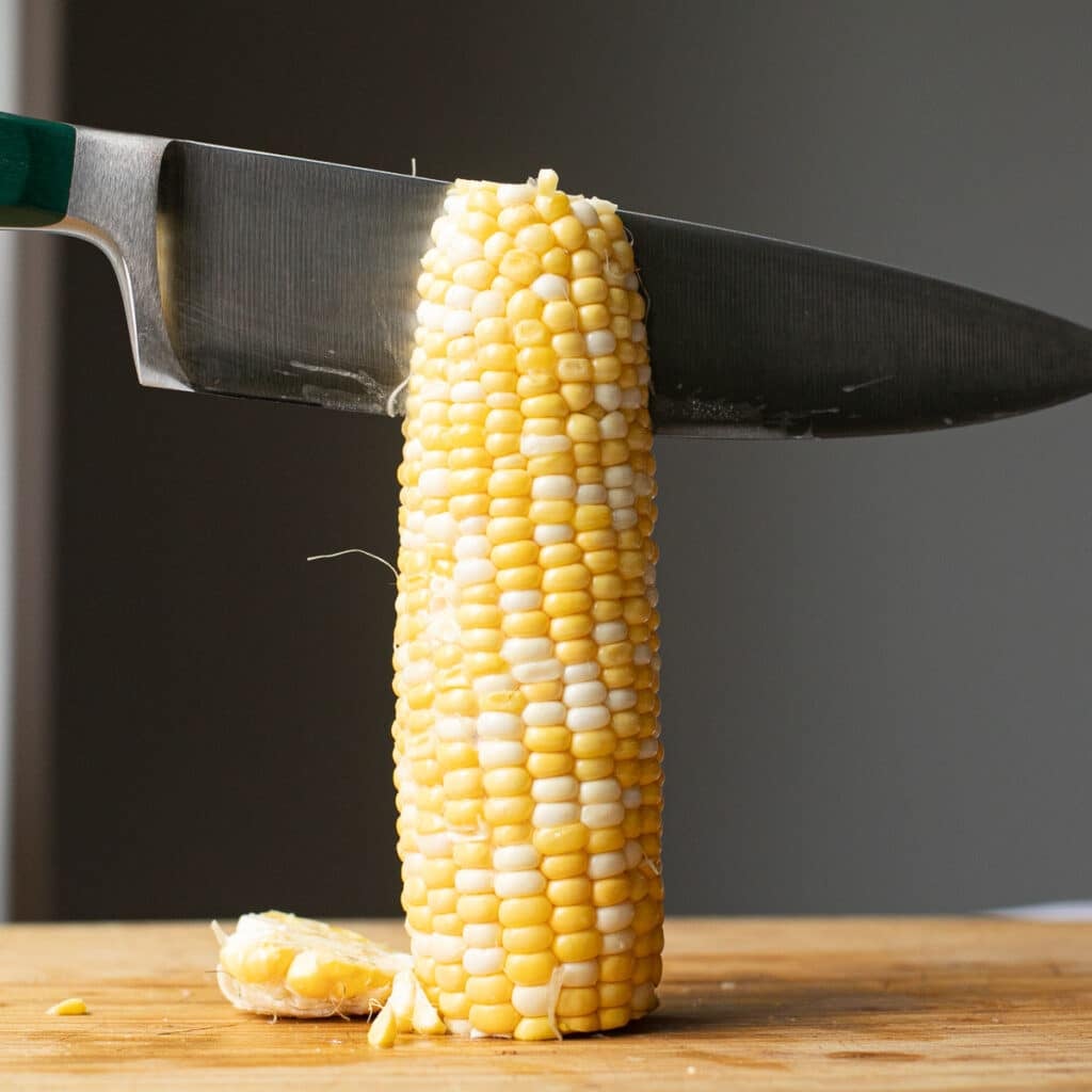 an knife cutting an ear of corn vertically