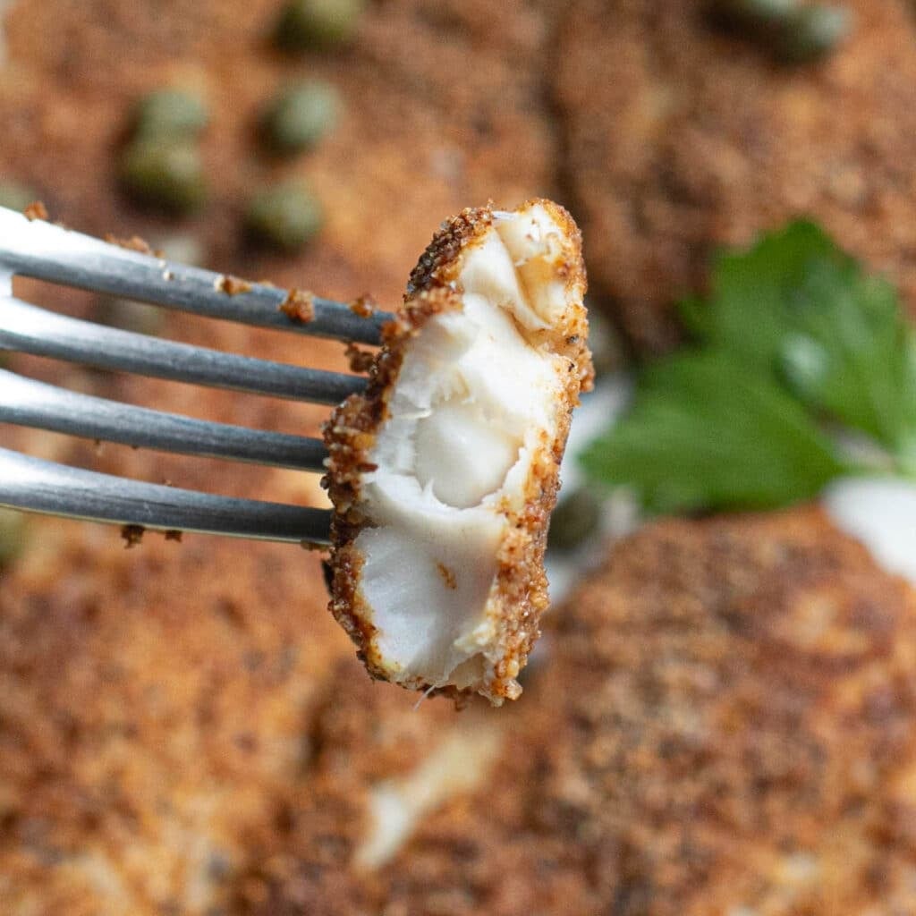 a fork holding a piece of air fryer flounder