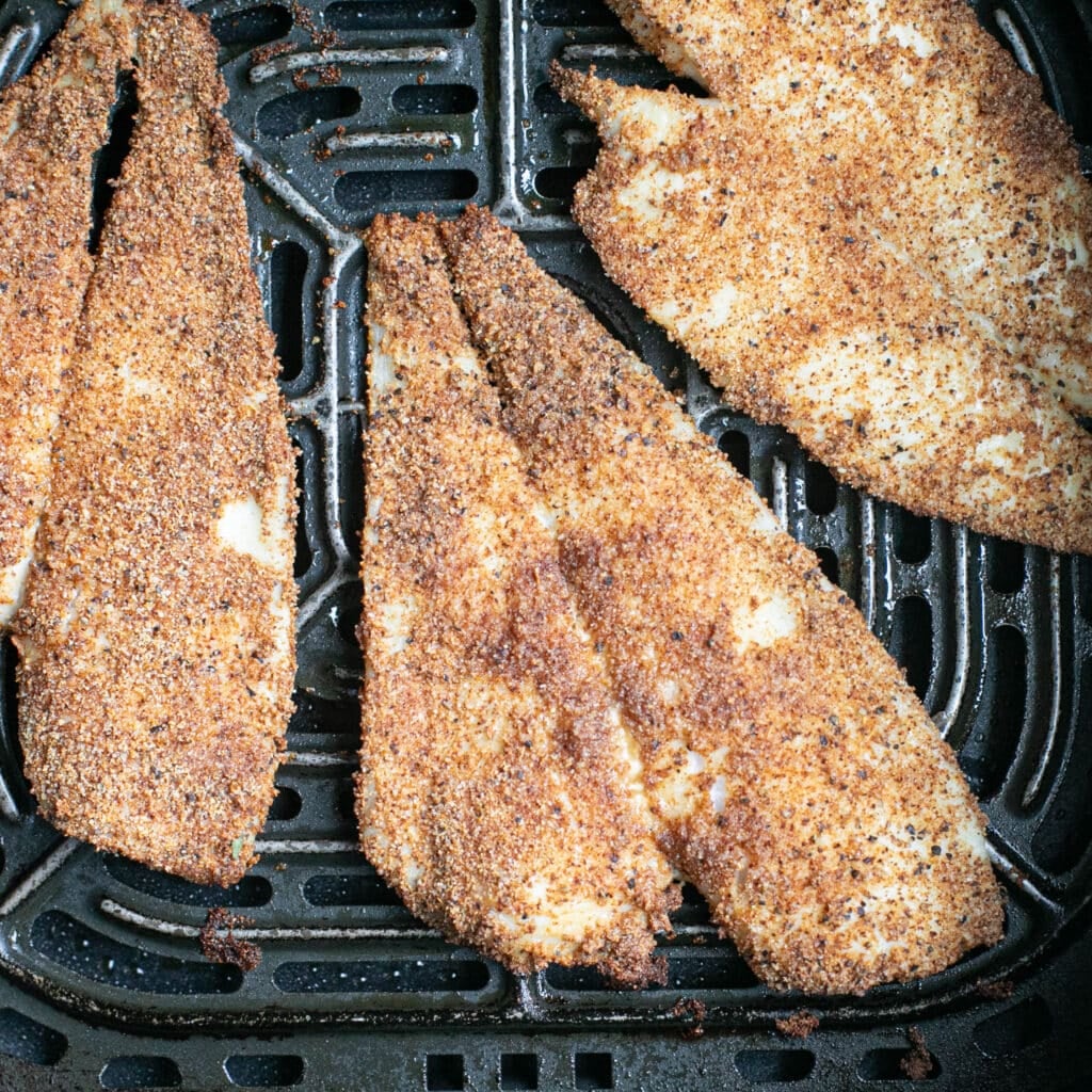 seasoned flounder fillets in an air fryer basket