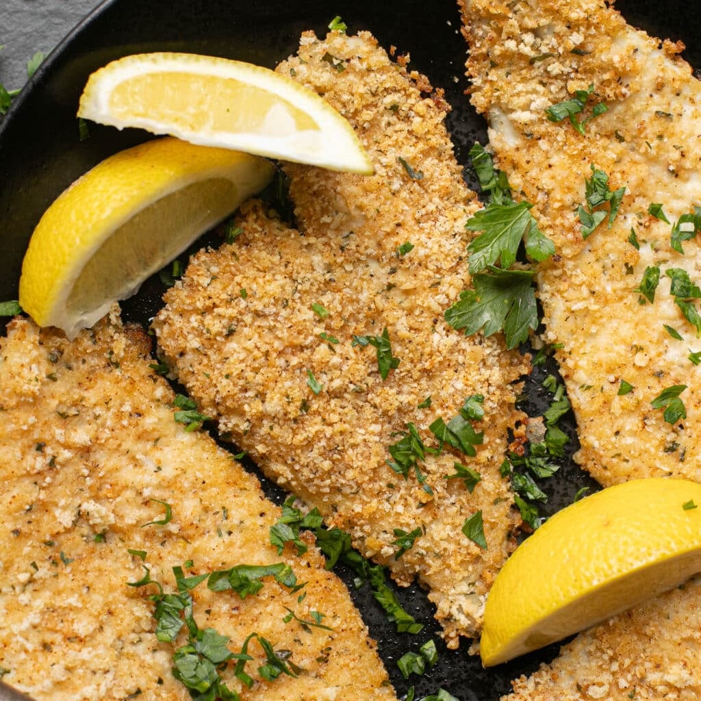 parmesan crusted baked flounder with fresh parsley and lemon wedges