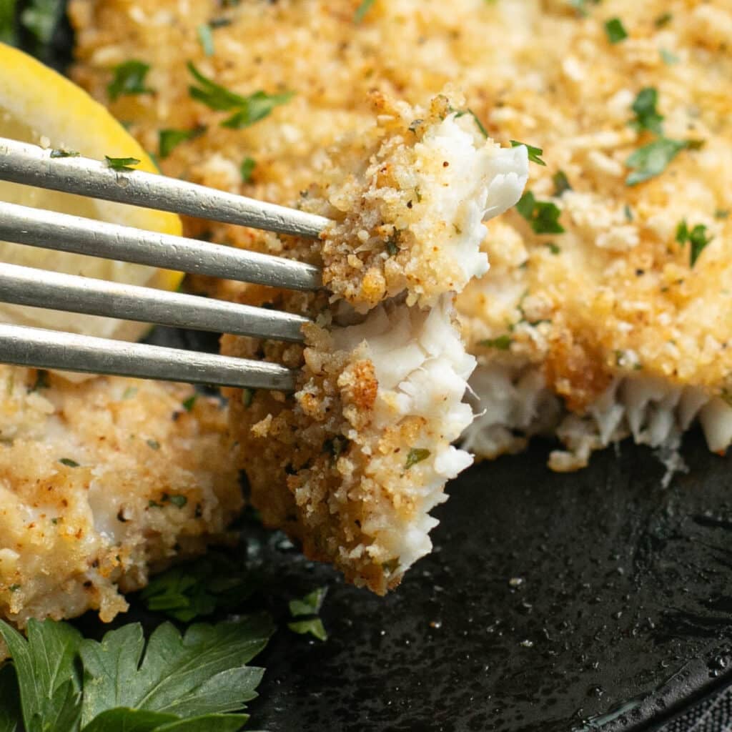a fork holding a bite of baked flounder