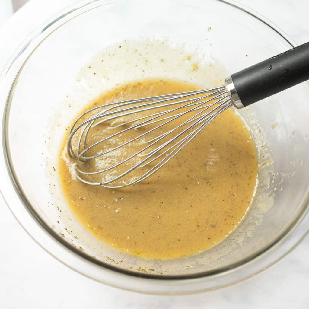 vinaigrette dressing in a glass bowl with a wire whisk