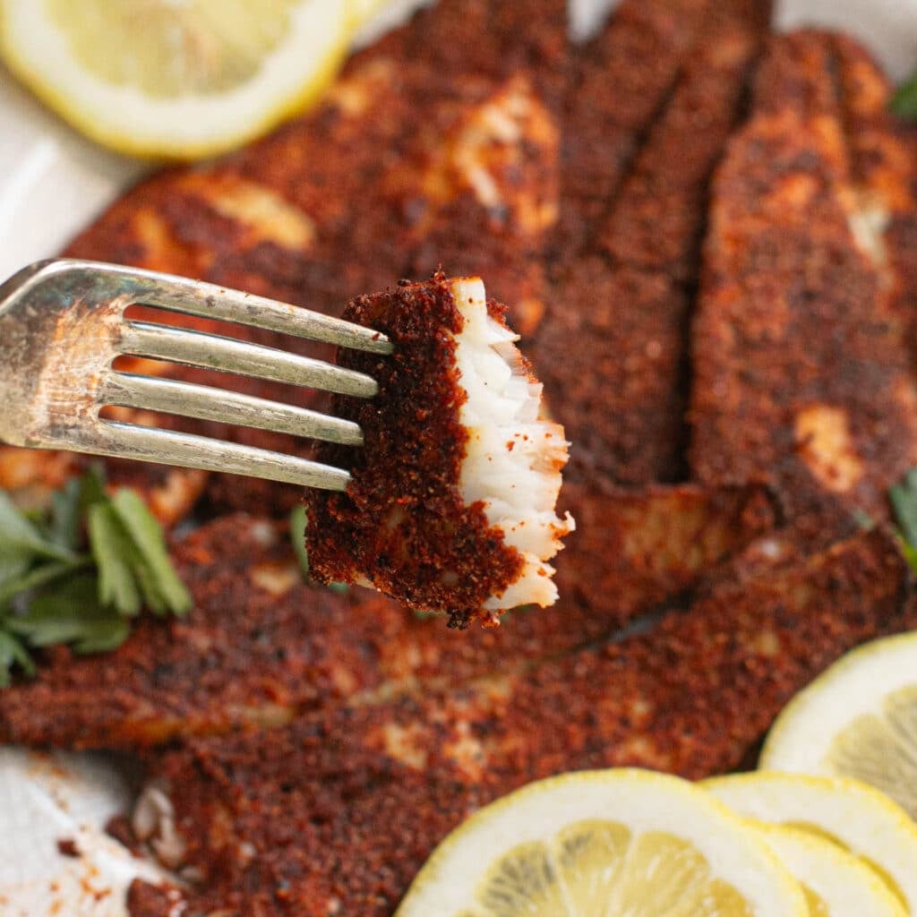 a fork holding a piece of air fryer tilapia