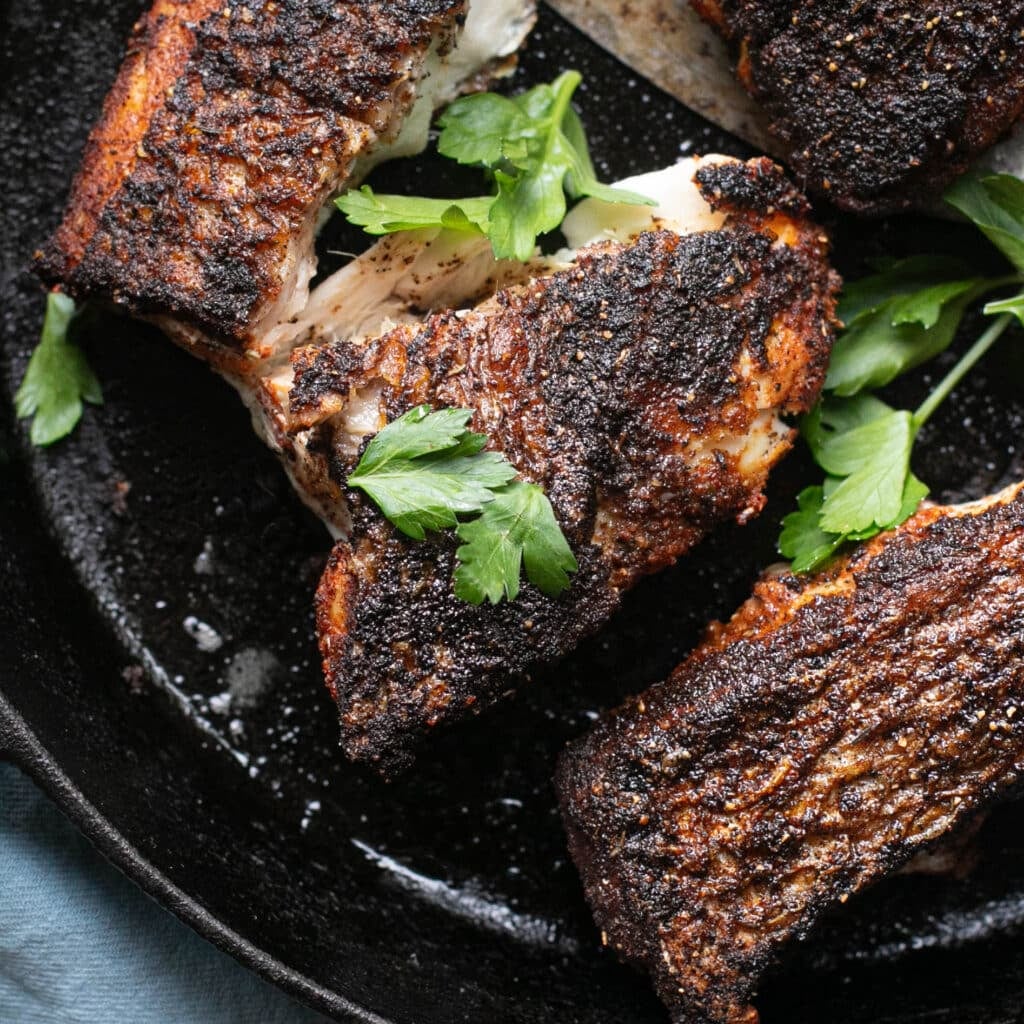 blackened snapper in a cast iron pan topped with fresh parsley