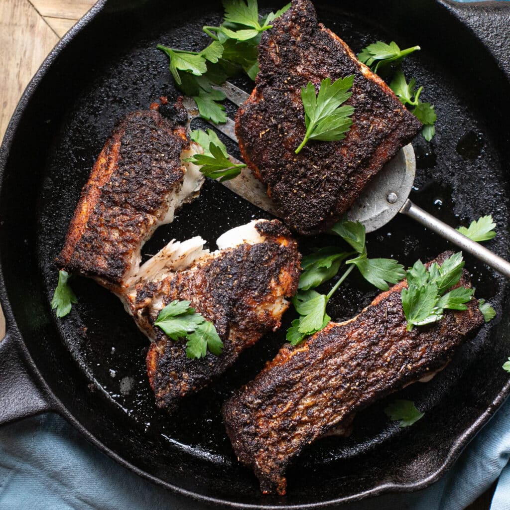 blackened snapper in a cast iron pan topped with fresh parsley