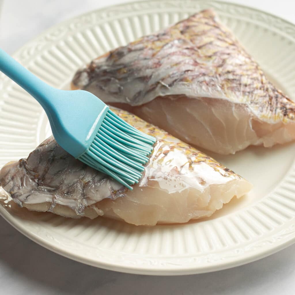 snapper fillet being brushed with oil
