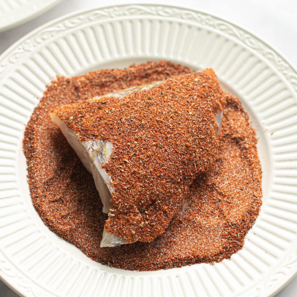 snapper fillet being coated in blackened seasoning