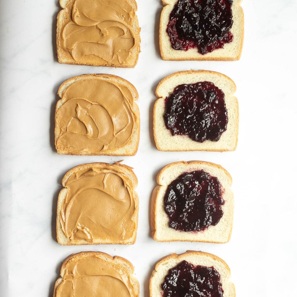 slices of white bread with peanut butter and grape jelly spread on them