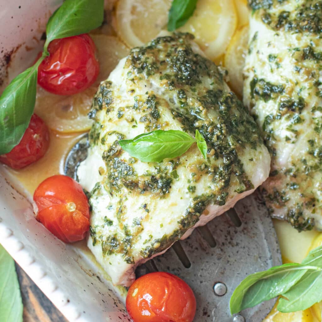 a fillet of snapper topped with pesto sauce and fresh basil