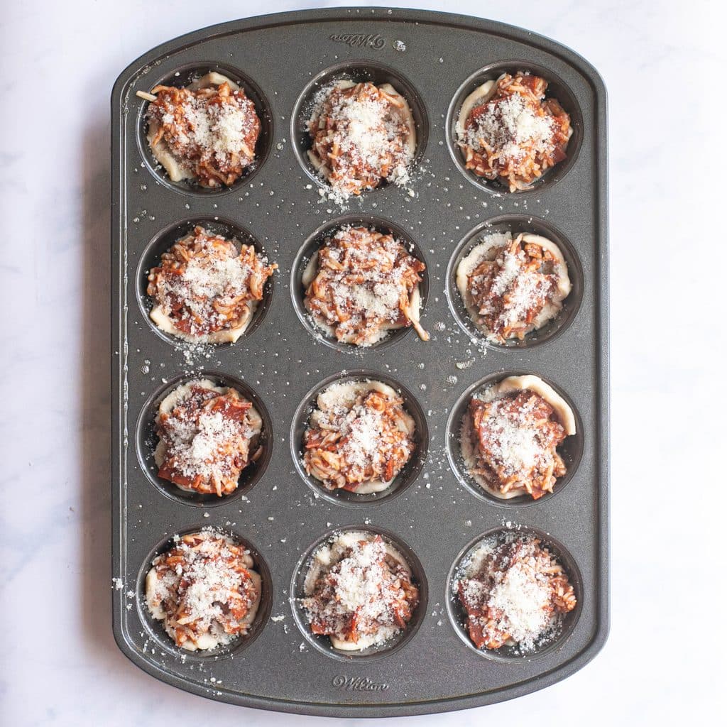 pizza muffins in a muffin tin before being baked