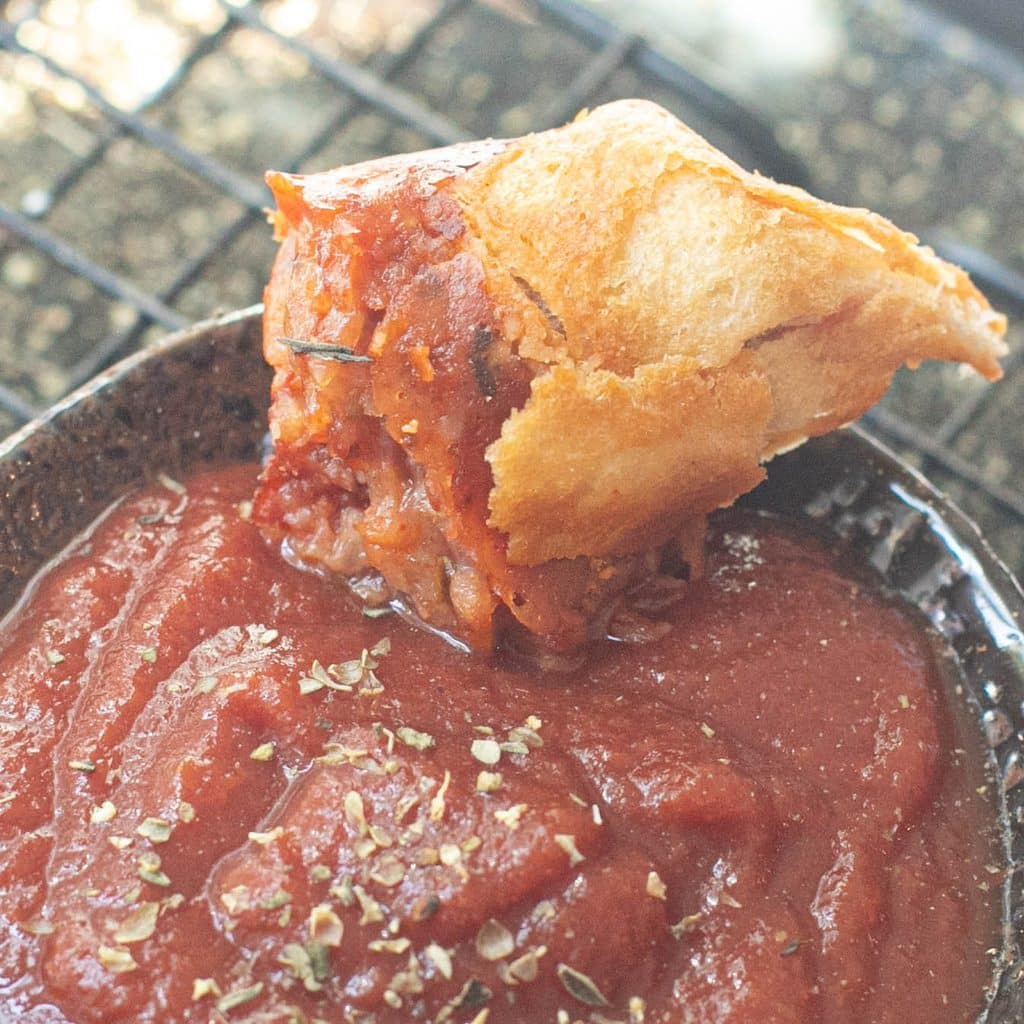 a piece of pizza muffin dipping into marinara sauce