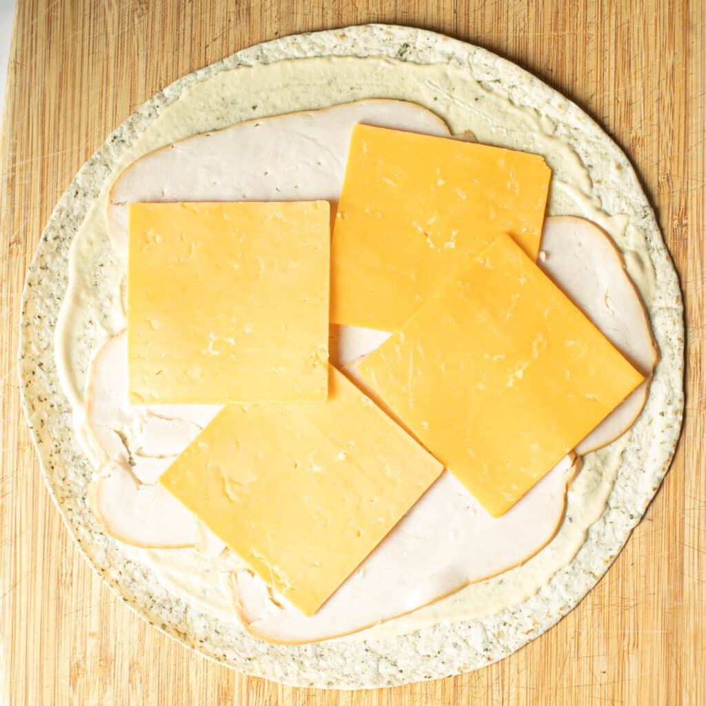 sliced cheese and turkey arrange on top of a flour tortilla