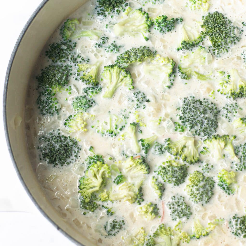 broccoli florets cooking in a creamy broth