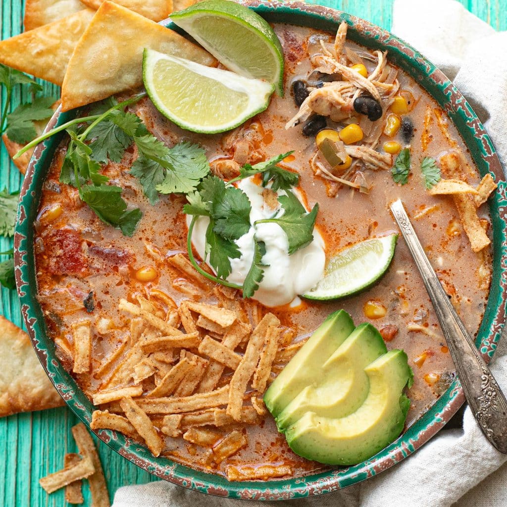 chicken tortilla soup topped with sour cream, lime wedges and cilantro