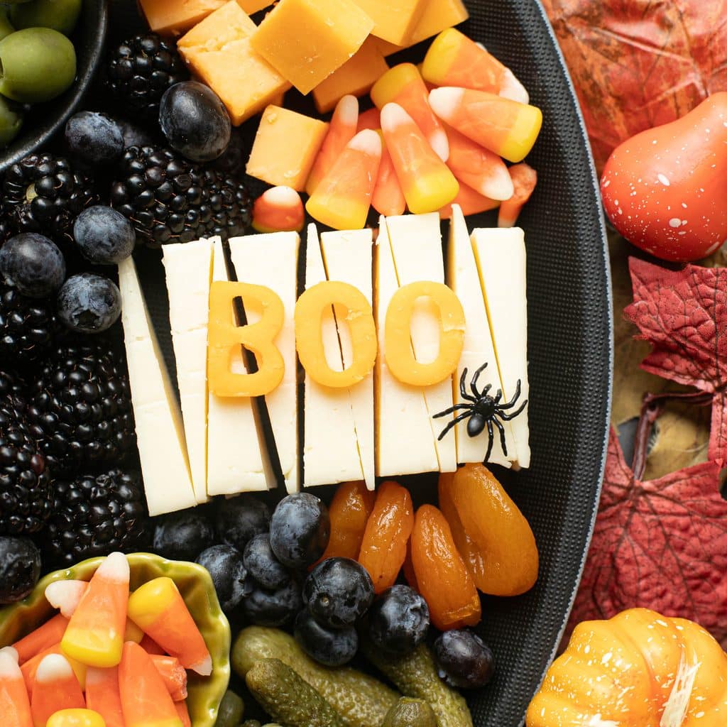 the word BOO cut out of cheese with a black plastic spider