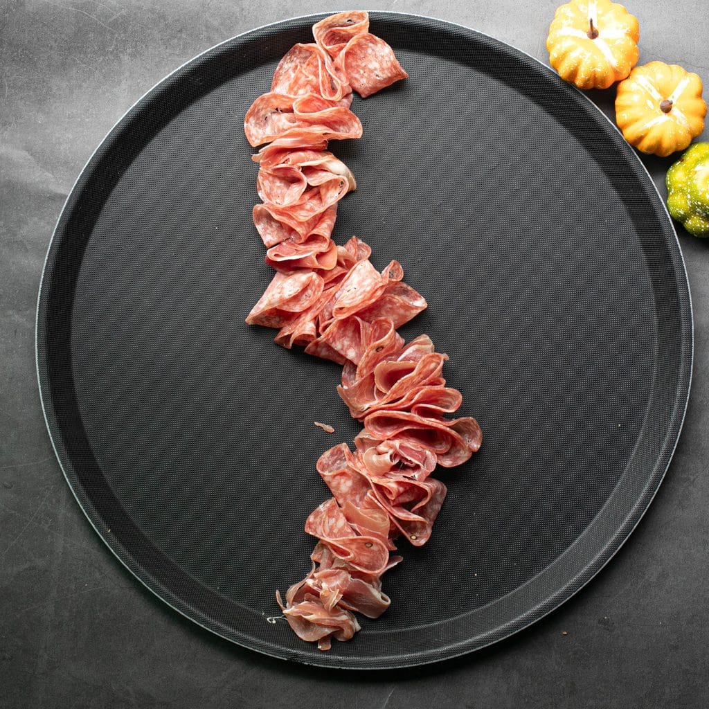 salami arranged in a wavy pattern on a round black serving tray
