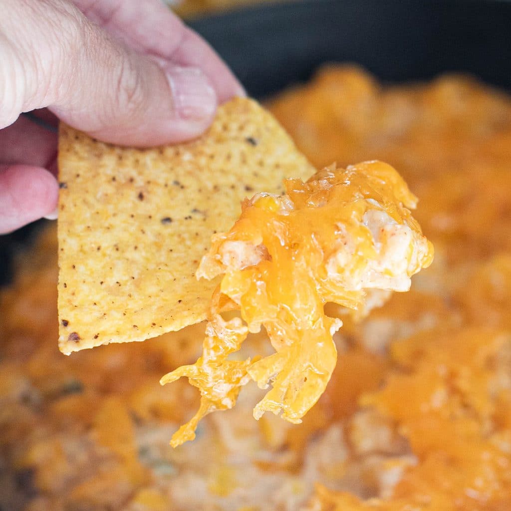 a tortilla chip with hot honey corn dip on it
