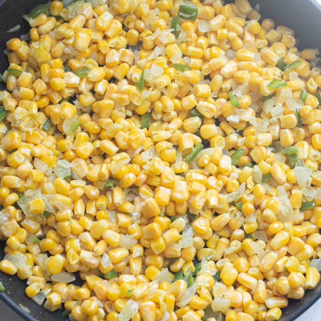 corn, onions and peppers cooking in a pan
