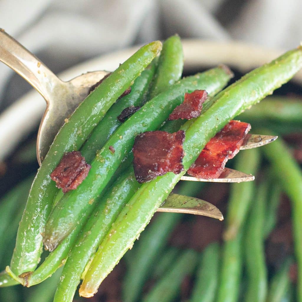 a large serving fork holding crack green beans