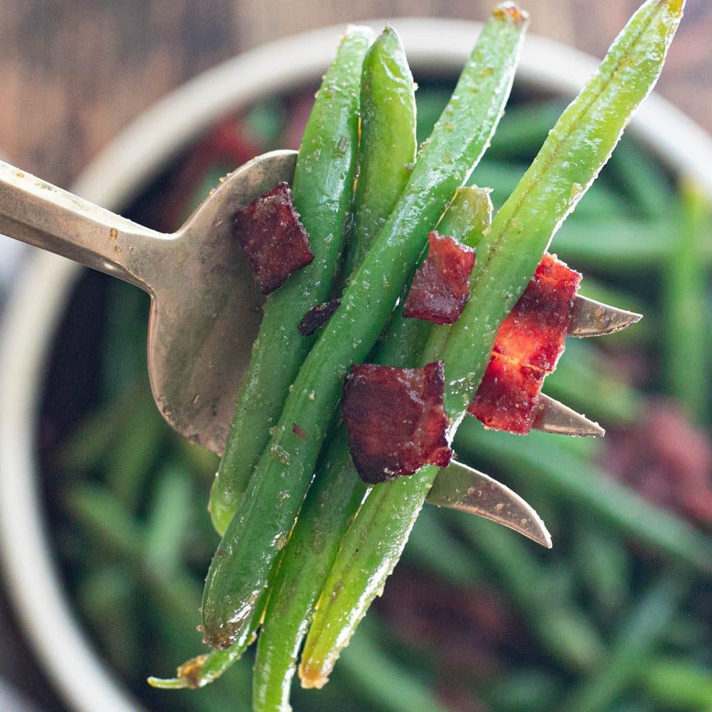 a large serving fork holding crack green beans