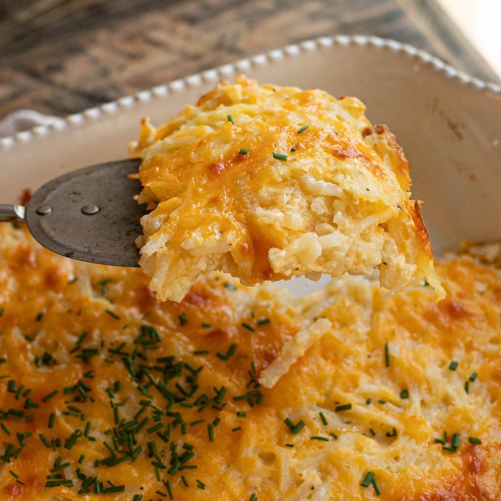 a spatula lifting a portion of Cracker Barrel hashbrown casserole out of the baking dish