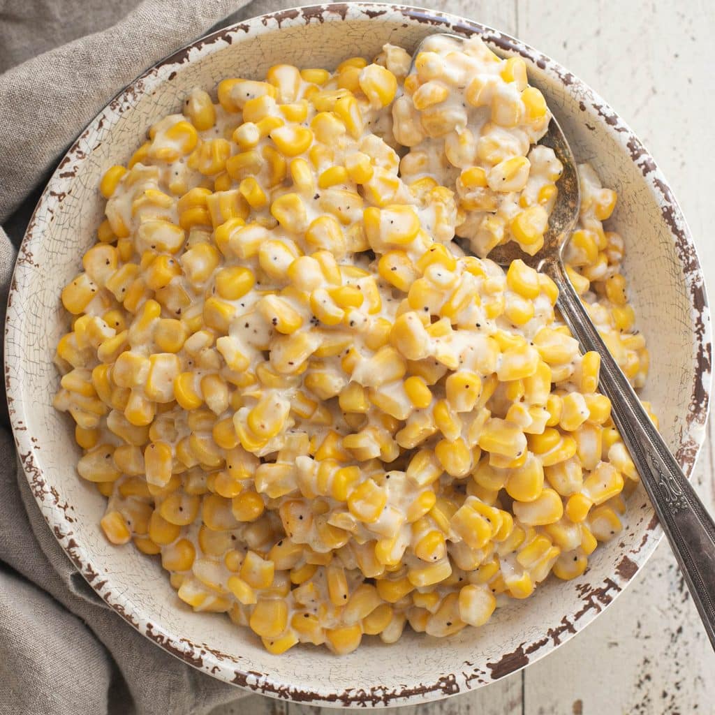 crockpot creamed corn in a white serving bowl