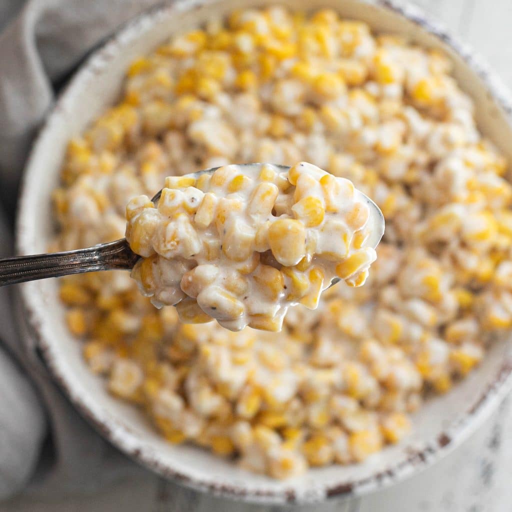 a large serving spoon holding crockpot creamed corn