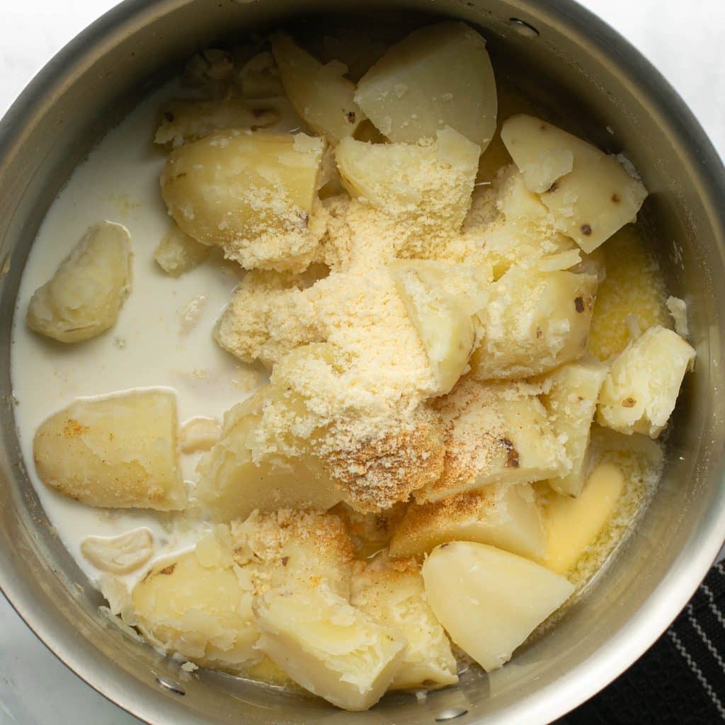 quartered cooked potatoes, Parmesan cheese and milk in a large pot